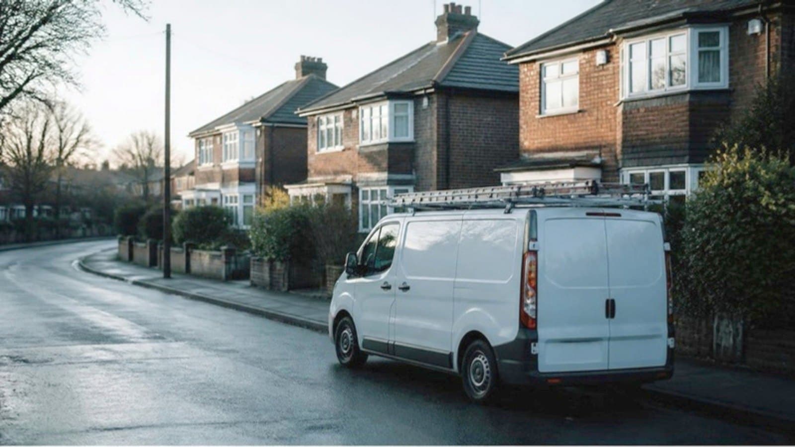 A white trade van parked on a wet residential street